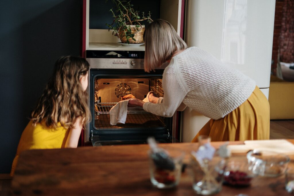 vrouw en kind gebruiken de oven in de keuken