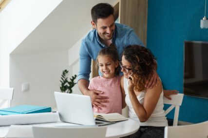 vader, moeder en dochter achter een laptop aan tafel